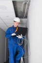A blue-uniformed master wiring a WiFi router in a hidden false ceiling system and verifying the correct installation via a laptop