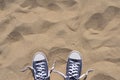 Blue unlaced sneakers on beach, top view Royalty Free Stock Photo