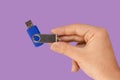 Blue USB flash memory on hand with isolated violet background