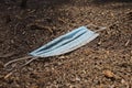 Blue used face mask covered in dirt lying on the ground Royalty Free Stock Photo