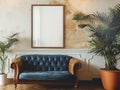 Blue velvet Chesterfield sofa in front of a blank picture frame and potted palm plants Royalty Free Stock Photo