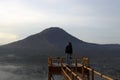 Blue view of the mountain on a misty morning at sunrise, with person standing alone on the natural wooden bridge