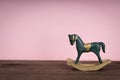 Blue vintage rocking horse on wooden floor. Pink background Royalty Free Stock Photo