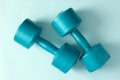 Blue vinyl dumbbells on blue background. Closeup. Top view