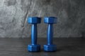 Blue vinyl dumbbells on table against grey background