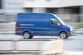 Blue Volkswagen Crafter cargo van with tall roof is driving on the street, side view. Light commercial vehicle in motion