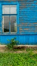 The blue wall of an old dilapidated wooden house and a glass window. The concept of living in a village in an ecologically clean Royalty Free Stock Photo