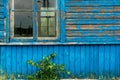 The blue wall of an old dilapidated wooden house and a glass window. The concept of living in a village in an ecologically clean Royalty Free Stock Photo