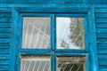 The blue wall of an old dilapidated wooden house and a glass window. The concept of living in a village in an ecologically clean Royalty Free Stock Photo