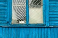 The blue wall of an old dilapidated wooden house and a glass window. The concept of living in a village in an ecologically clean Royalty Free Stock Photo