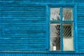 The blue wall of an old dilapidated wooden house and a glass window. The concept of living in a village in an ecologically clean Royalty Free Stock Photo