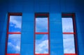 Blue wall with three red windows reflecting sky Royalty Free Stock Photo