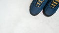 Blue warm winter or autumn sneakers with orange shoe laces on white concrete surface, top view. Copy space. Flat lay Royalty Free Stock Photo