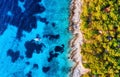 Blue water background and coast with forest from top view. Yacht on the water surface from top view. Summer seascape from air. Cro