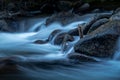 Blue water flowing over the rocks in a mountain stream Royalty Free Stock Photo