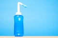 Blue water pulse nasal wash bottle on blue background, nasal irrigation concept