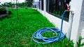 Blue water rubber tube connected to the hose on the white fences Royalty Free Stock Photo