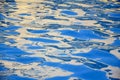 Blue water surface of pool with bizarre waves. Fantastic abstract reflections and glare on water. Close-up. Copy space