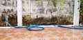 Blue water tap and water hose putting on orange title floor with dirty cement wall in house Royalty Free Stock Photo