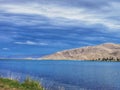 Blue waters of Lake Ruataniwha on the South Island of New Zealand under moody cloudy sky