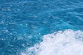 Blue wavy sea with white foam close to shore. View down. Bali, Nusa Penida, Indonesia. Splashing foam at right down corner of