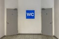 Blue WC sign on the white wall with two toilet doors