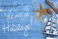 Blue weathered wood with maritime decoration and message we are on holidays Royalty Free Stock Photo