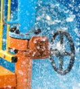 Blue wheel valve with pipe and wather flooding around in summer Royalty Free Stock Photo