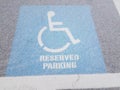 Blue wheelchair reserved parking sign on black asphalt with white snow Royalty Free Stock Photo