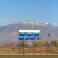 Blue and white baseball scoreboard above the chain link fence at a sports field