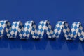 A blue and white bavarian paper streamer are lying on a blue ground Royalty Free Stock Photo
