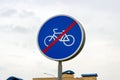 Blue and white bicycle lane sign with red forbid line indicating the end of the bike route, large round roadside traffic signage. Royalty Free Stock Photo