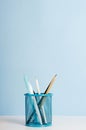Blue, white and black pencils, pens in a stand on a white table on a blue background, office desk. Copy space Royalty Free Stock Photo