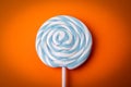 Blue and white candy on a stick, lollipop. Orange background Royalty Free Stock Photo