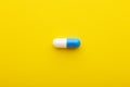 Blue white capsule pill on yellow background Royalty Free Stock Photo
