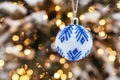 Blue white christmas ball on fir tree branch close up golden yellow light bokeh Royalty Free Stock Photo