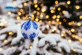 Blue white christmas ball on fir tree branch close up golden yellow light bokeh Royalty Free Stock Photo