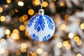 Blue white christmas ball on fir tree branch close up golden yellow light bokeh Royalty Free Stock Photo