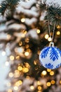 Blue white christmas ball on fir tree branch close up golden yellow light bokeh Royalty Free Stock Photo