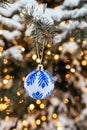 Blue white christmas ball on fir tree branch close up golden yellow light bokeh Royalty Free Stock Photo