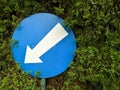 Blue and white circle arrow sign with background of green leaves