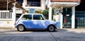 Blue/White classic Mini cooper parked on the street  in front of home`s entrance door with sunlight Royalty Free Stock Photo
