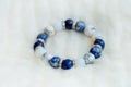 Blue and white color tone lucky fortune stone bracelet include which Lapis lazuli, Sodalite, Howlite and Moonstone on white wool b Royalty Free Stock Photo