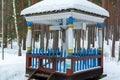 The blue and white crucifix covered with snow in a winter forest