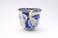 Blue and white decorated cup repaired with the antique kintsugi real gold technique Royalty Free Stock Photo