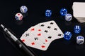 Blue and white dices and cards with electronic sigarette on black glossy background Royalty Free Stock Photo