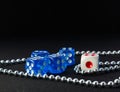 Blue and white dices and metal chain on dark background