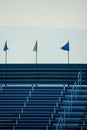 Blue and white flags flying above stadium bleachers for sports games like football, baseball or soccer