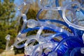 A blue and white glass sculpture on top of a water fountain with lush green trees at Atlanta Botanical Garden