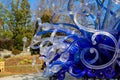 A blue and white glass sculpture on top of a water fountain with lush green trees at Atlanta Botanical Garden